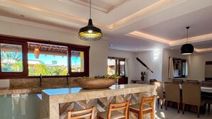 A spacious kitchen with a large island, wooden chairs, and a dining area with a table and chairs. - Pousada Refúgio Verde Trancoso (Porto Seguro)