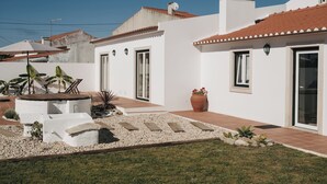 A modern house with a white exterior, red-tiled roof, and a well-maintained garden with gravel pathways and potted plants. - Country House (Serra do Bouro)
