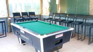 A pool table in a room with chairs arranged around it. - White House Lounge & Accommodation  (Eldoret)