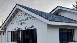 A building labeled "WHITE HOUSE ACCOMMODATION & MEALS" with a sign for "KOT NELEL LOUNGE" at the entrance. - White House Lounge & Accommodation  (Eldoret)