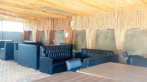 A room with a wooden ceiling, black leather seating, and a wooden table. - White House Lounge & Accommodation  (Eldoret)