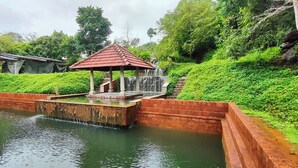 A serene garden with a small pavilion, a water feature, and lush greenery. - HORTUS MALABARICUS RESORT (Talappilly)