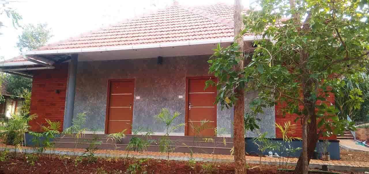A building with a tiled roof, two doors, and a small garden area with plants.