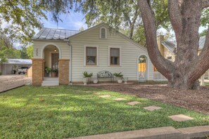 A two-story house with a brick entrance, a large tree in front, and a well-maintained lawn.
