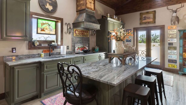 Una cocina con una isla grande, techo de madera y decoración con temática tejana.