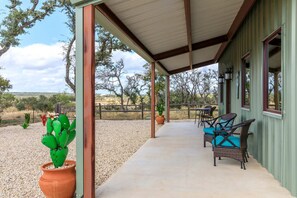 Un porche techado con muebles de exterior, un cactus y vistas del paisaje circundante.