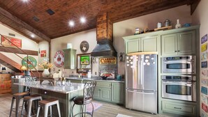 Una cocina con una isla central, taburetes de bar, estufa y refrigerador.