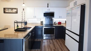 A modern kitchen with white cabinets, stainless steel appliances, and a wooden countertop. - Stylish 3-bed, 2-bath modern condo in Coeur d'Alene, perfect for up to 6 guests. Enjoy a fully equipped kitchen, king suite, and community steam sauna & gym. 12 mins from downtown CDA, 20 mins to Silverwood Theme Park, and 40 mins to Spokane! (Coeur d'Alene)