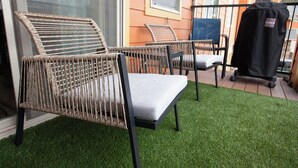 Wicker chairs with cushions on a green lawn, a barbecue grill, and a building with orange siding. - Stylish 3-bed, 2-bath modern condo in Coeur d'Alene, perfect for up to 6 guests. Enjoy a fully equipped kitchen, king suite, and community steam sauna & gym. 12 mins from downtown CDA, 20 mins to Silverwood Theme Park, and 40 mins to Spokane! (Coeur d'Alene)
