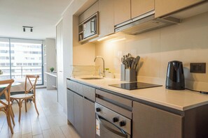 A modern kitchen with a built-in microwave, stainless steel appliances, a coffee maker, and a dining area with chairs and a table.