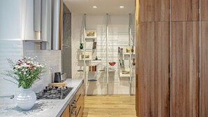 A modern kitchen with a wooden cabinet, a marble countertop, and a built-in oven. - At Manuela's Luxury Apartment  (Roma)