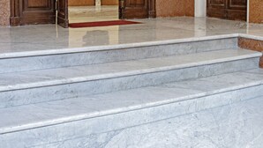 A marble staircase leading to a room with wooden doors and a bulletin board on the wall. - At Manuela's Luxury Apartment  (Roma)