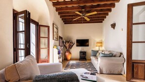 A living room with a sofa, a coffee table, a TV, a fireplace, and a ceiling fan. - Casa de Medina: a spacious Andalusian townhouse in the heart of Medina Sidonia (Medina-Sidonia)