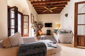 A living room with a sofa, a coffee table, a TV, a fireplace, and a ceiling fan.