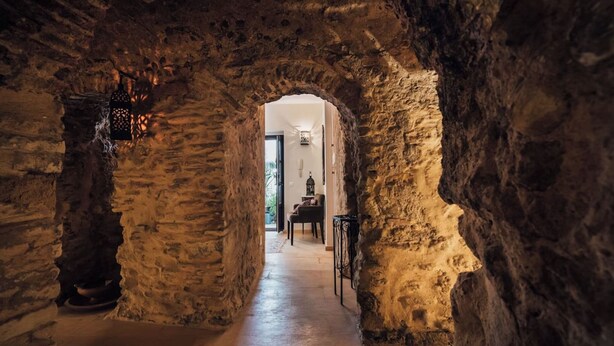 A stone archway leading to a room with a chair and a table. - Casa de Medina: a spacious Andalusian townhouse in the heart of Medina Sidonia (Medina-Sidonia)