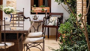 A courtyard with a table and chairs, a potted plant, and a stone archway. - Casa de Medina: a spacious Andalusian townhouse in the heart of Medina Sidonia (Medina-Sidonia)
