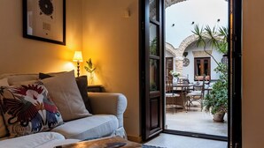 A bedroom with a bed, a reading area with a book, a lamp, and a view of an outdoor patio with a table and chairs. - Casa de Medina: a spacious Andalusian townhouse in the heart of Medina Sidonia (Medina-Sidonia)
