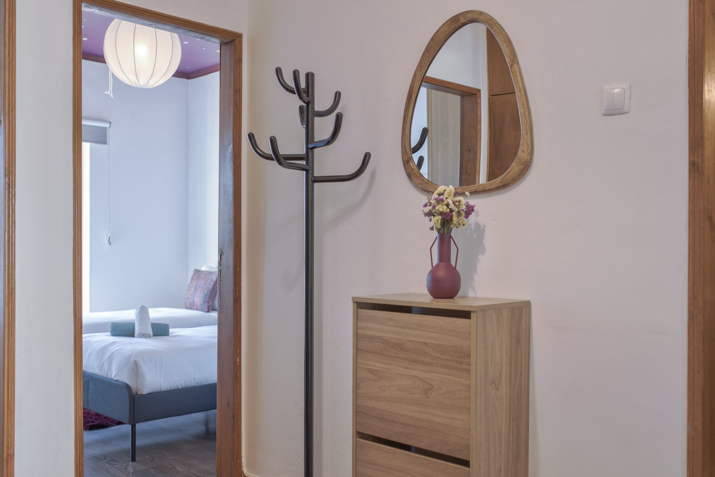 Habitación de hotel con tocador de madera, perchero y espejo.
