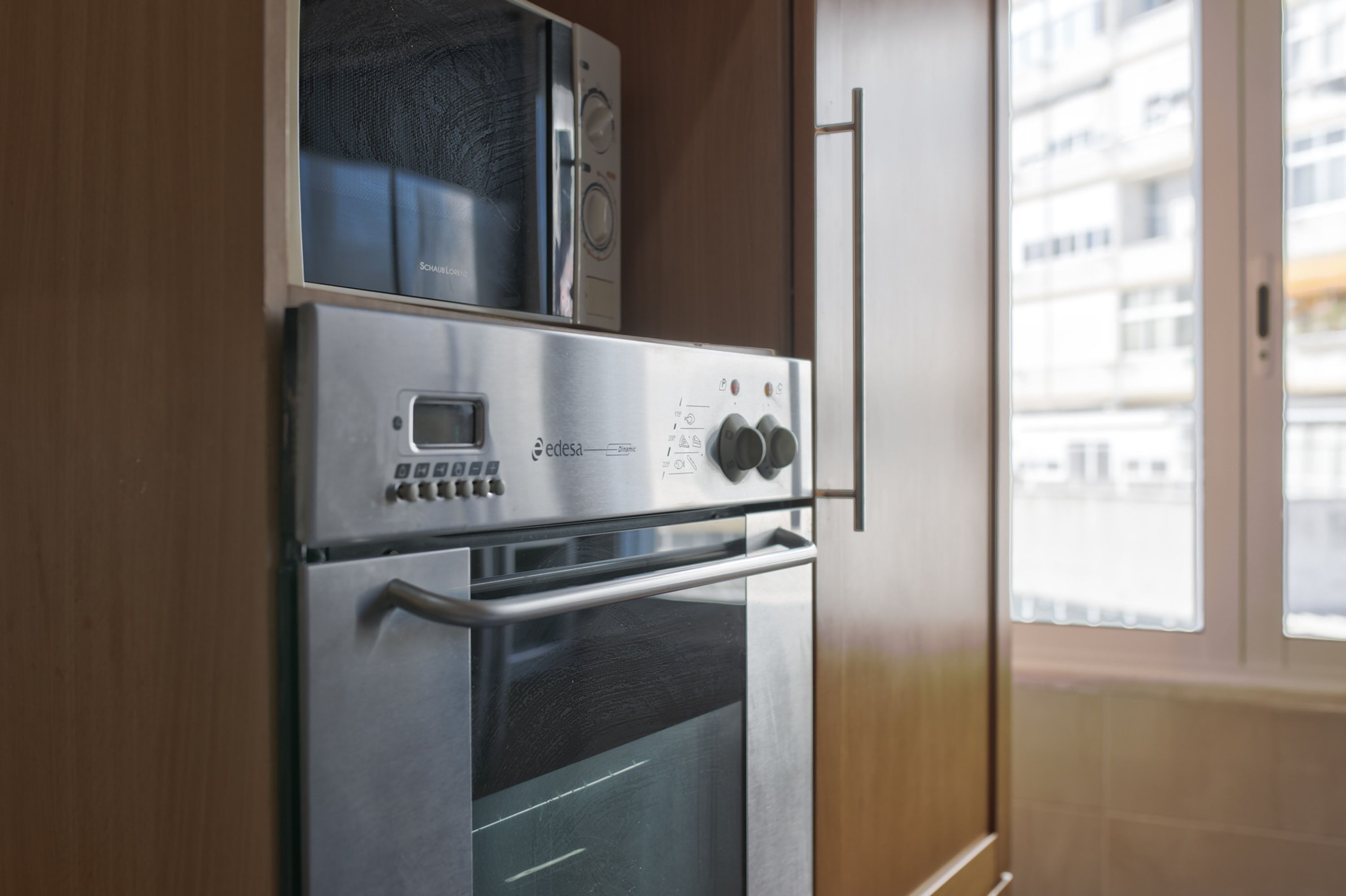 Cocina compacta con microondas integrado, horno y panel de control digital.