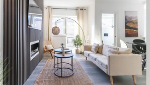 A modern living room with a sofa, two side tables, a large mirror, and a hanging light fixture. - Rato Prime Terrace BY Homing (Lisbon)