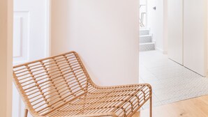 A wicker chair in a hallway with white walls and wooden flooring. - Alfama Design W Terrace by Homing (Lisbon)