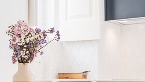 A kitchen with a white countertop, wooden chairs, a woven chair seat, a vase with flowers, and a stove. - Alfama Design W Terrace by Homing (Lisbon)