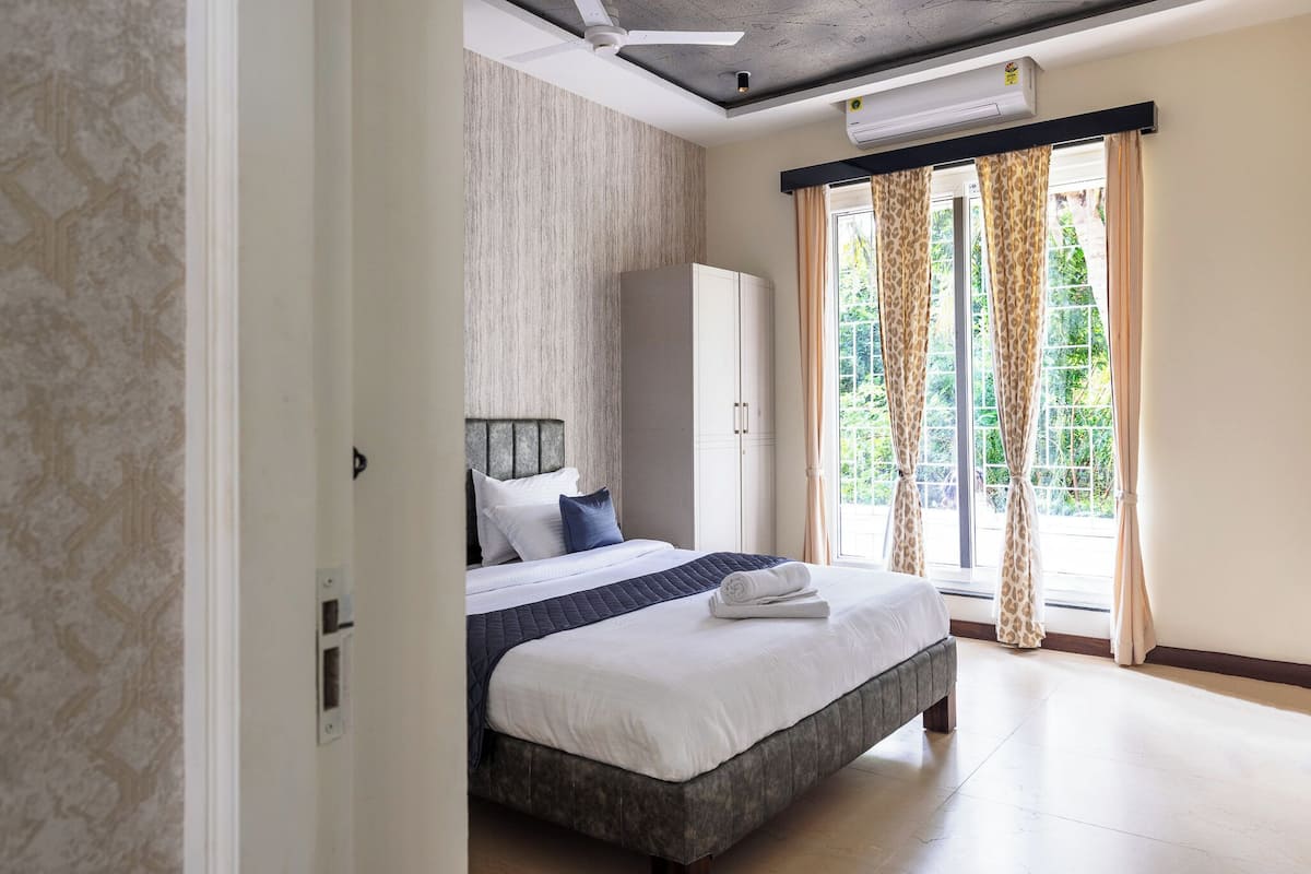 Ein Schlafzimmer mit einem Bett, einem Kleiderschrank und einem Fenster mit Vorhängen.
