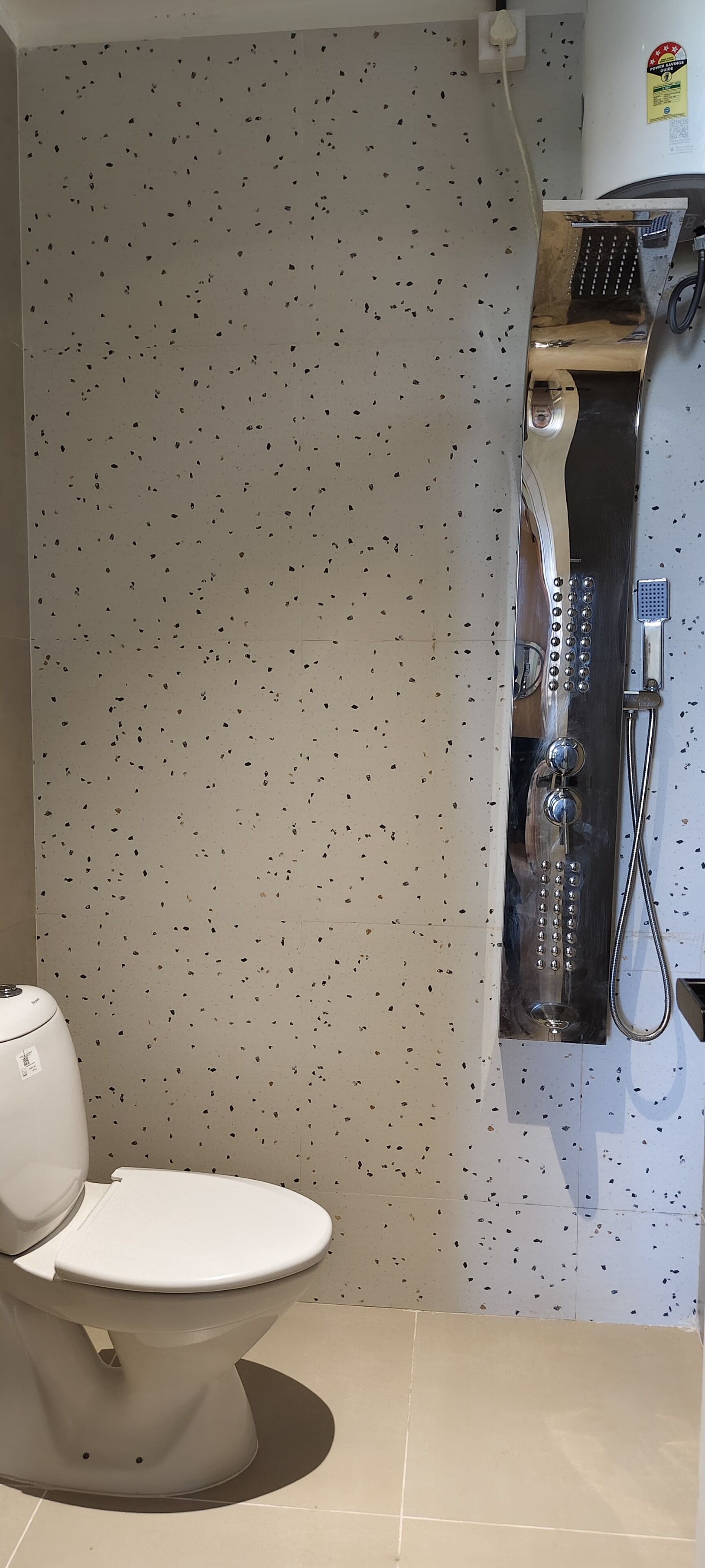 Ein Badezimmer mit Toilette, Duschkabine und Fliesenwand.