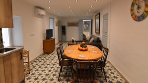 A dining area with a round table, chairs, and a clock on the wall. - Casa Los Anafes - in the heart of the village (Cómpeta)