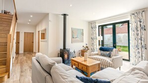 A modern living room with a sofa, a coffee table, and a fireplace. - Home Farm Holiday Homes (Nuneham Courtenay)