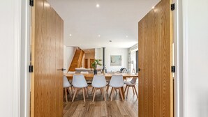 A modern dining area with a wooden floor, white chairs, and a central table. - Home Farm Holiday Homes (Nuneham Courtenay)