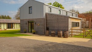 A modern two-story building with a grey exterior, large windows, and a wooden door. - Home Farm Holiday Homes (Nuneham Courtenay)