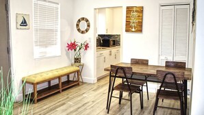 Una cocina moderna con armarios blancos, un microondas negro y una mesa de comedor de madera con cuatro sillas.