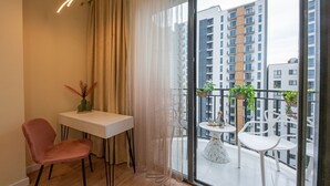 A balcony with a table and chairs, a potted plant, and a view of high-rise buildings.