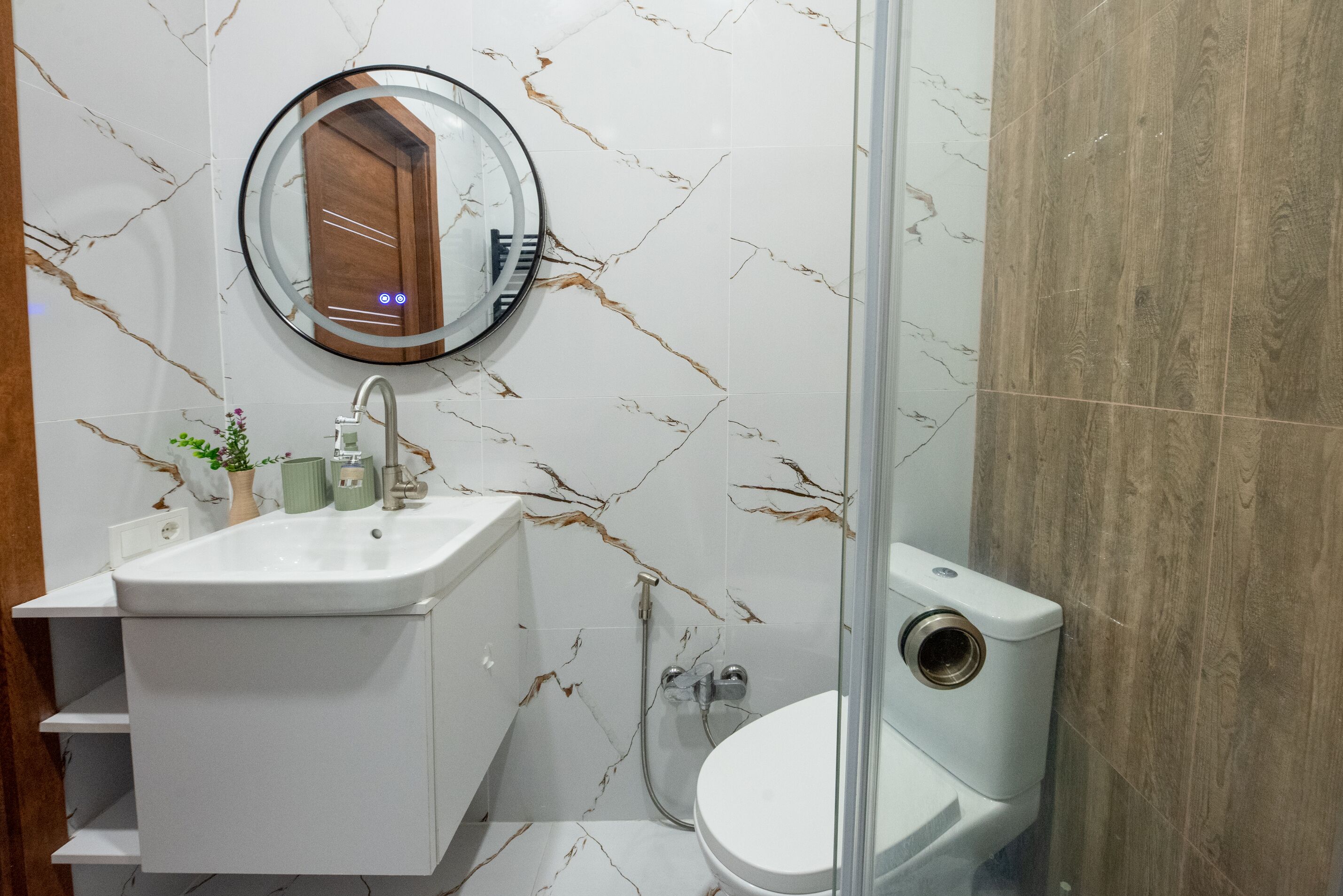 Un baño con lavamanos blanco, un espejo, un inodoro y una zona de ducha.