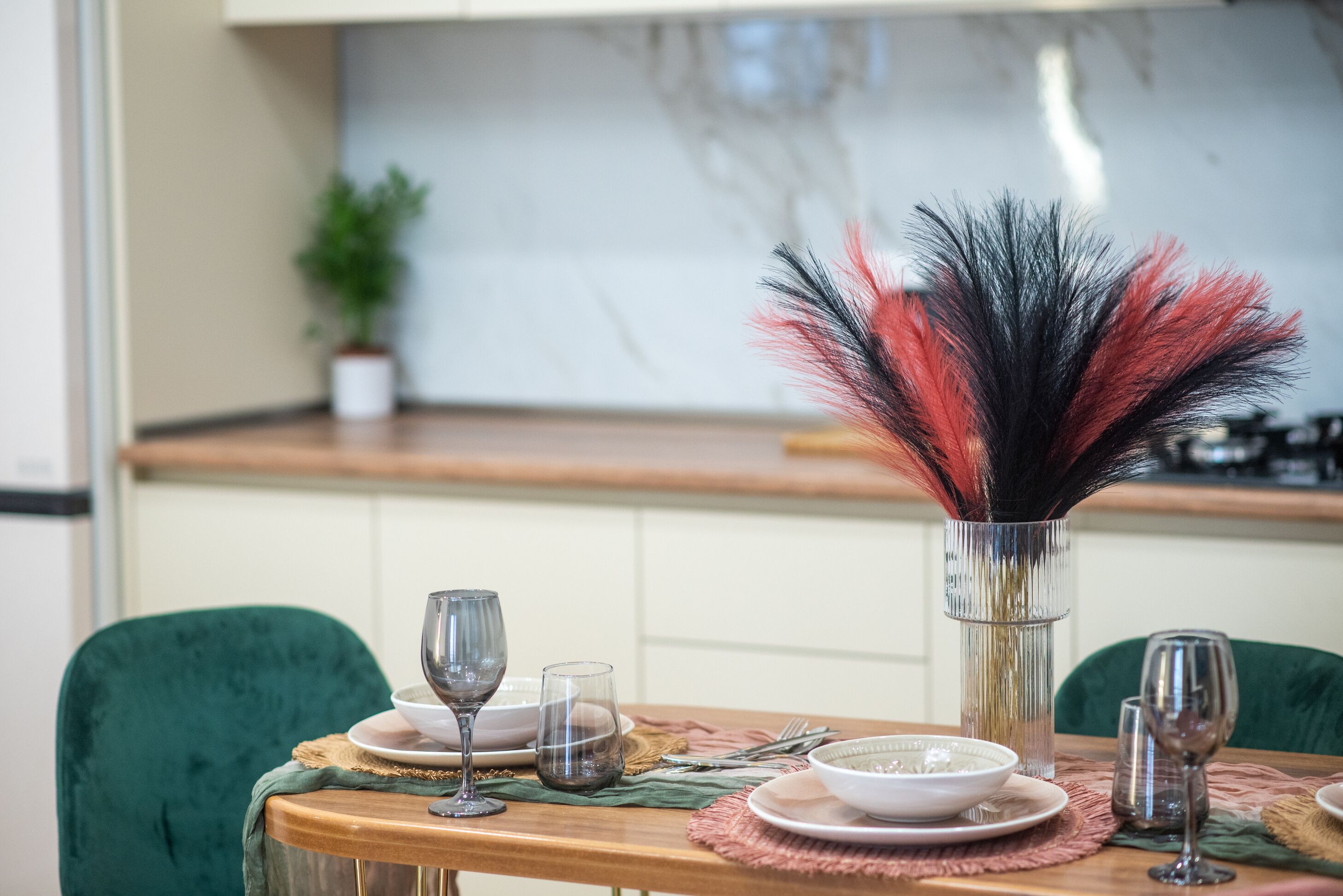 Tavola imbandita con piatti, bicchieri e un'elegante composizione di piume.