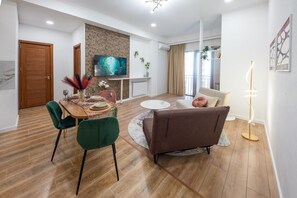 A modern living room with a dining area, wooden flooring, a sofa, a coffee table, and a TV. - HB apartments Nutsubidze (Tbilisi)