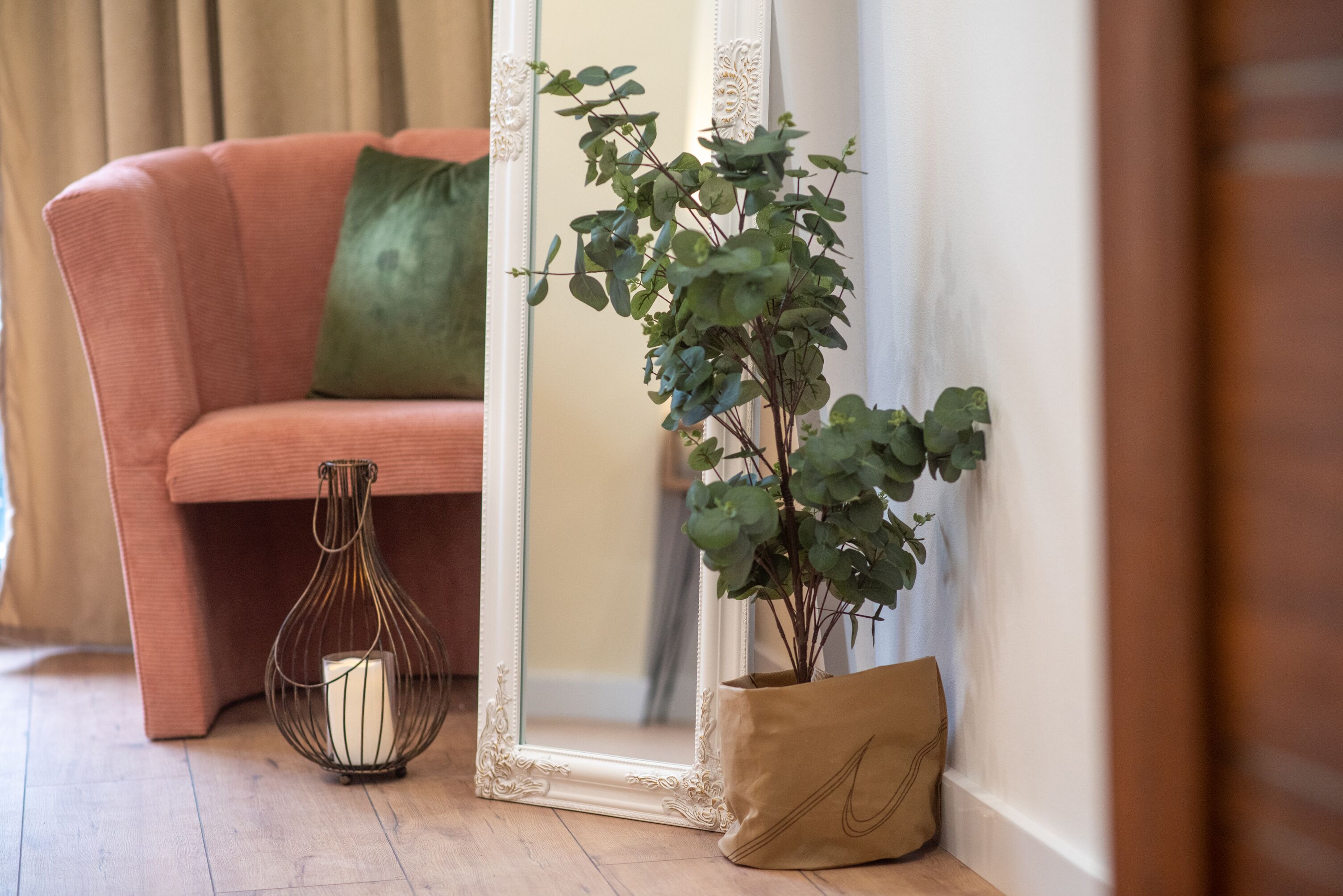 Un rincón de una habitación con un sofá, un espejo, una vela en un candelabro y una planta en maceta.