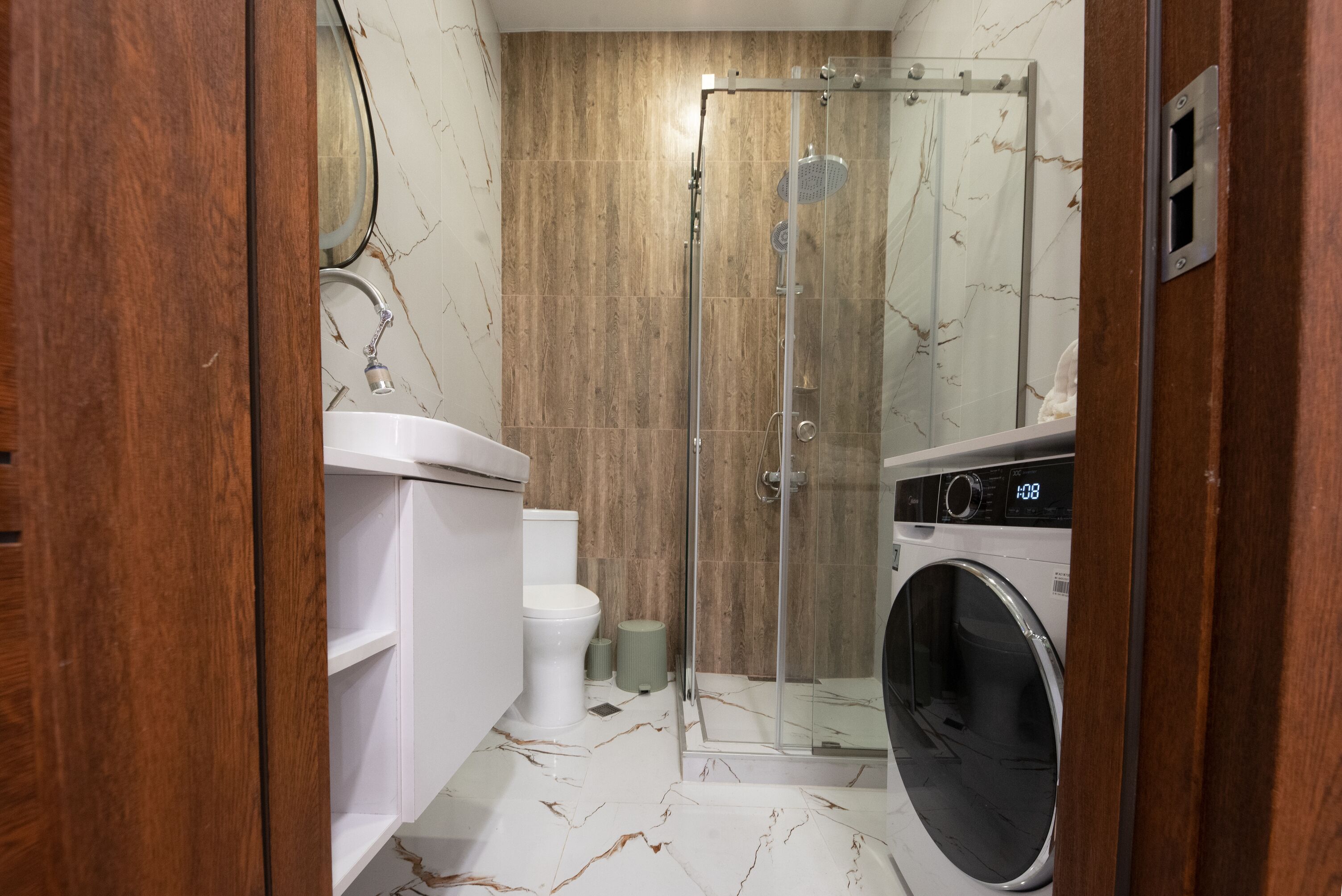 A bathroom with a toilet, sink, shower, and washing machine.