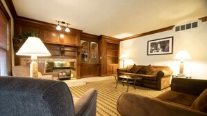 A cozy living room with a fireplace, wooden cabinets, and a comfortable sofa set.
