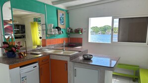 Une cuisine équipée d’un évier, d’un plan de travail et d’une fenêtre donnant sur la mer.