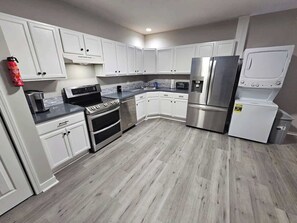 Une cuisine moderne avec des meubles blancs, des appareils en acier inoxydable et un plancher en bois gris.