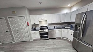 A modern kitchen with white cabinets, a stainless steel refrigerator, a built-in oven, and a microwave. - Private Apartment in Southbury 103 (Southbury)