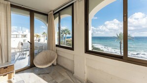 Ein Balkon mit Meerblick, einem Stuhl und einer weißen Wand.
