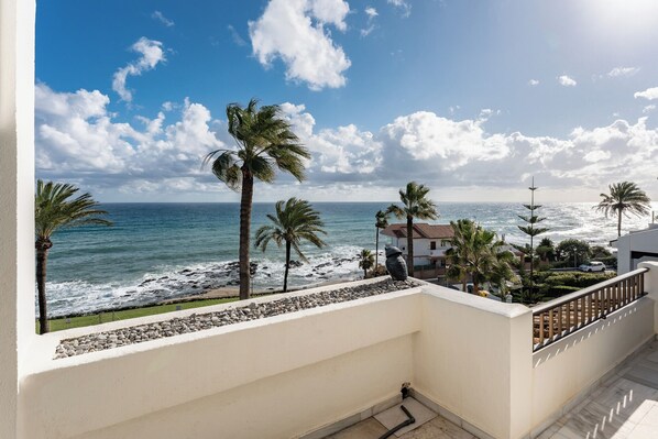 A balcony with a view of the ocean, palm trees, and a building with a red roof. - CT 262 - Flamingo Views (Mijas)