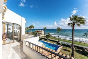 Un balcone con vista sull'oceano, una piscina e palme.