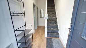 A staircase with a dark carpeted floor leading to a door with a 'Welcome' sign.