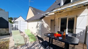 Une terrasse avec une table, des chaises et une bouteille.