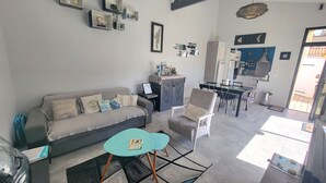 A modern living room with a sofa, armchair, and a dining area with a table and chairs. - Renovated house with garden and terrace in La Chaume, near beach, WiFi (Les Sables-d'Olonne)