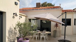 An outdoor patio with a table and chairs, a large umbrella, and potted plants. - Renovated house with garden and terrace in La Chaume, near beach, WiFi (Les Sables-d'Olonne)